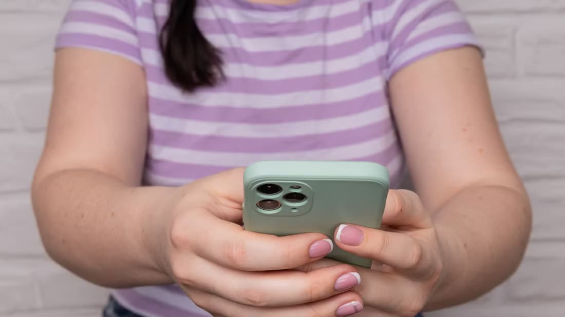 a-child-holding-an-iphone-14-pro كيفية تخصيص رسائل الرد التلقائي على المكالمات في iPhone