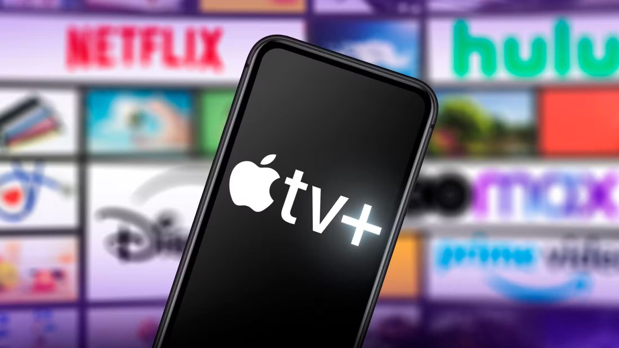 a-phone-with-the-apple-tv-logo-on-the-screen-and-in-the-background-several-screens-with-logos-of-other-streaming-services-scaled أخيرًا، تطبيق Apple TV+ يصل إلى Android: استمتع بأفضل المسلسلات والأفلام اليوم