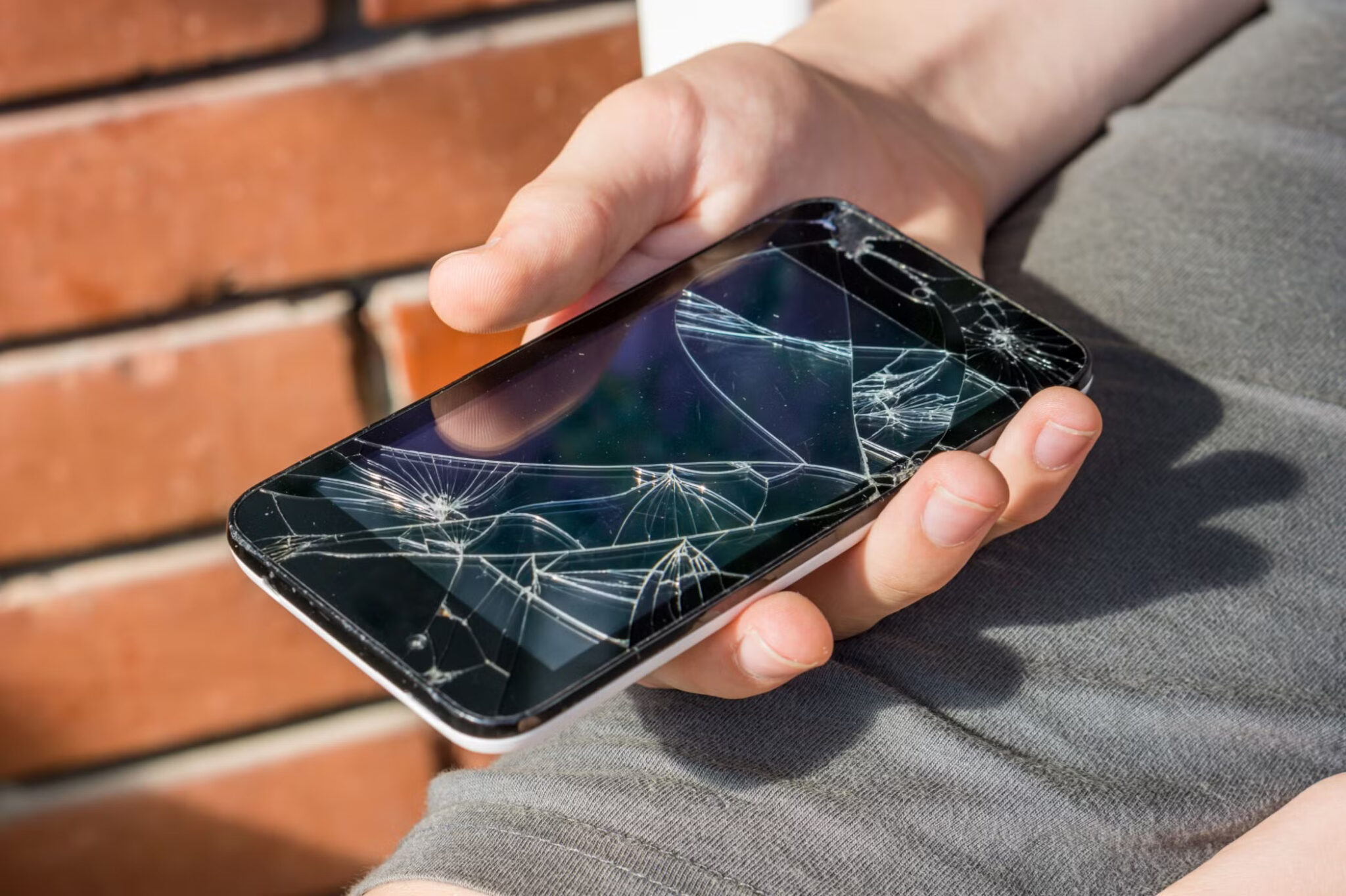 close-up-of-a-boy-s-hand-looking-at-his-still-working-phone-with-a-broken-screen-scaled لماذا الهواتف الخالية من المنافذ هي المستقبل وكيف ستغير طريقة استخدامنا للتكنولوجيا